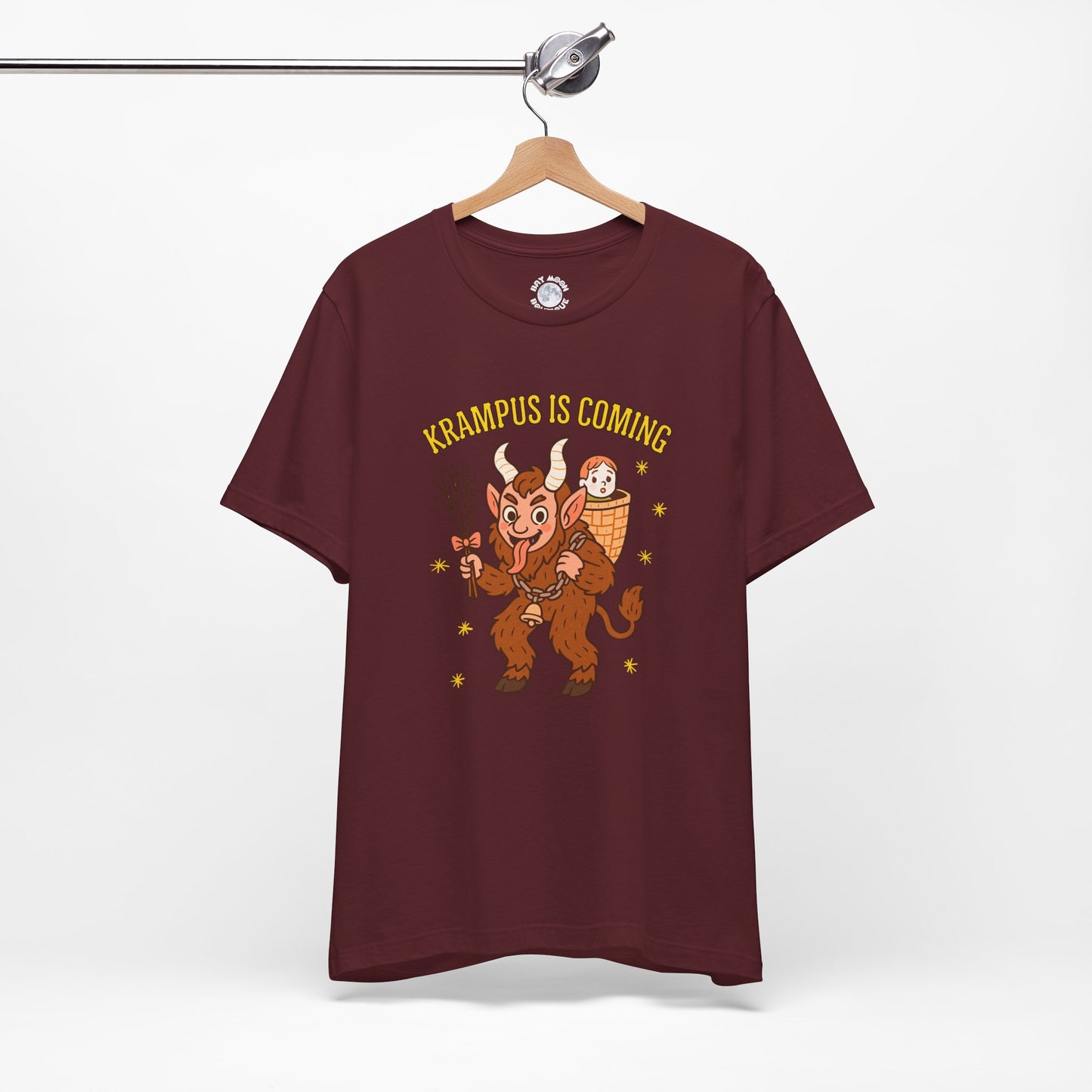 Maroon t-shirt with Krampus graphic and text 'Krampus is Coming' on a hanger against a white background