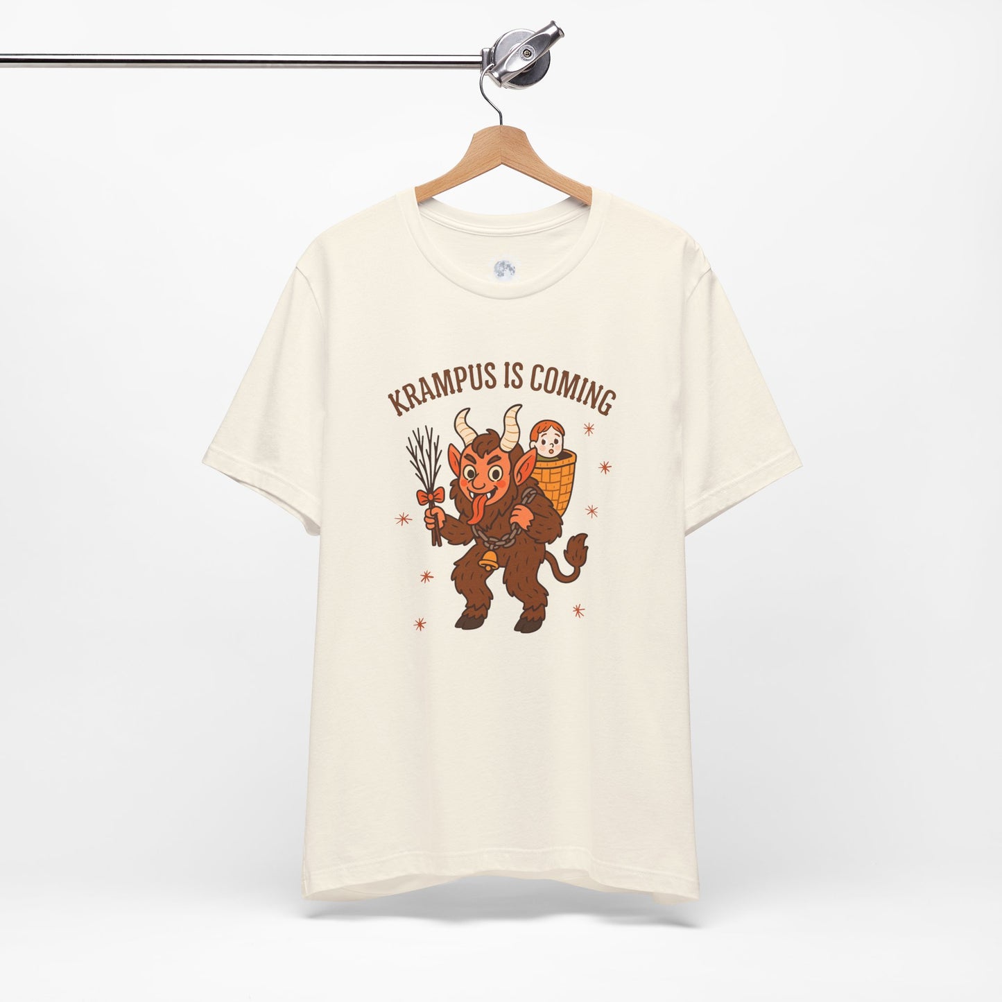 Beige t-shirt with Krampus graphic and text 'Krampus is Coming' on a hanger against a white background
