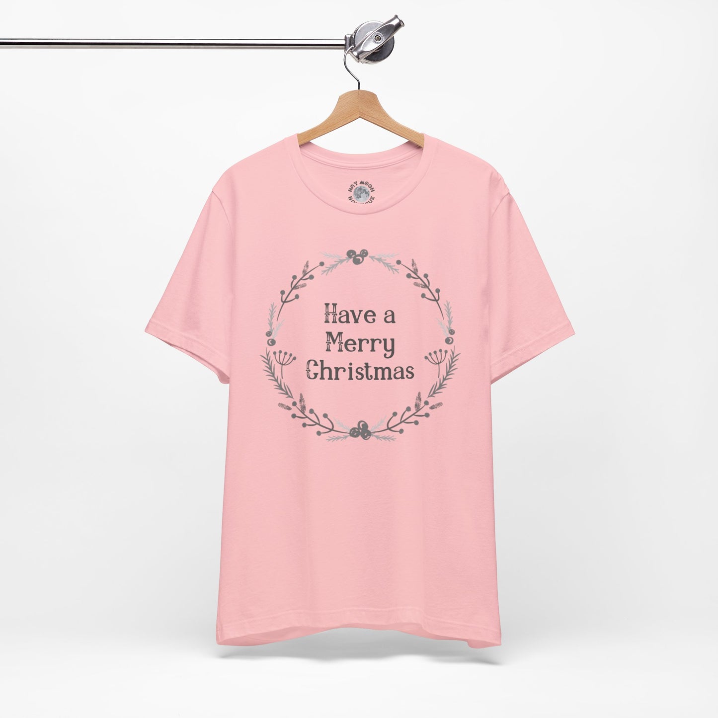 Pink t-shirt with 'Have a Merry Christmas' text on a hanger against a white background