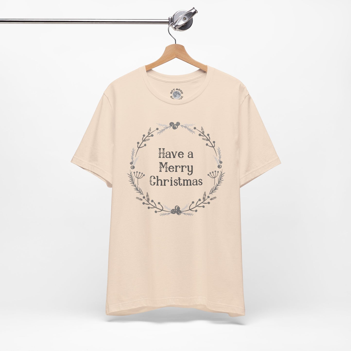 Beige t-shirt with 'Have a Merry Christmas' text on a hanger against a white background