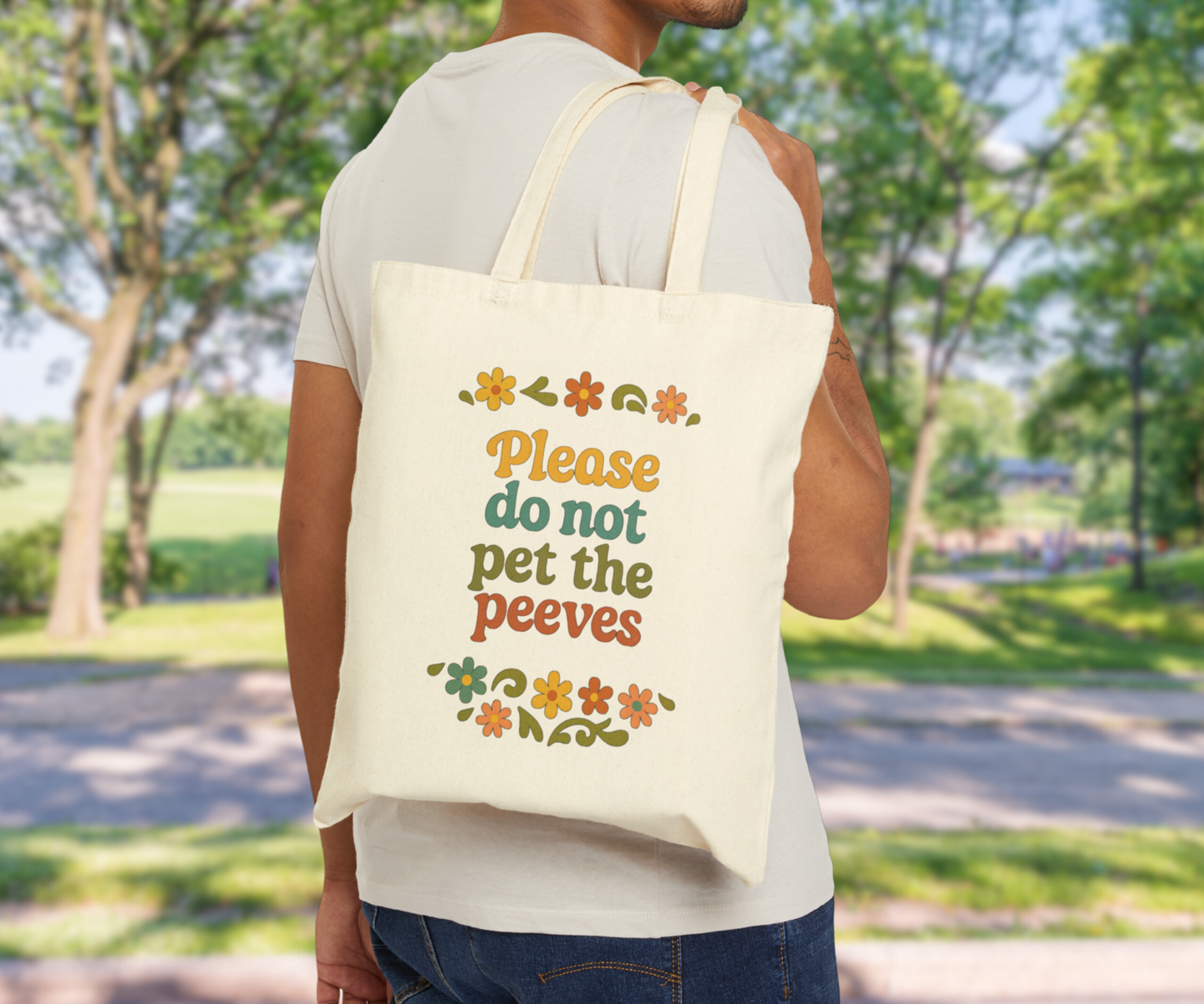 Person holding a tote bag with text please do not pet the peeves and floral designs outdoors