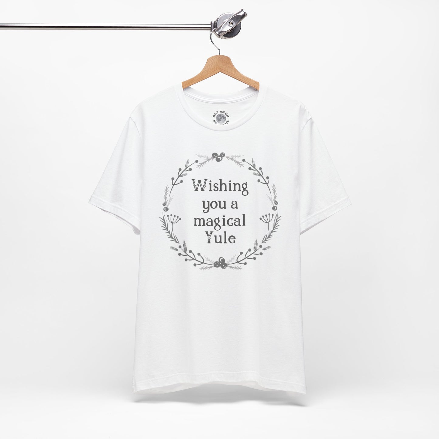 White t-shirt with 'Wishing you a magical Yule' text on a hanger against a white background